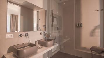 A modern bathroom with two sinks, a glass-enclosed shower, and a large mirror.