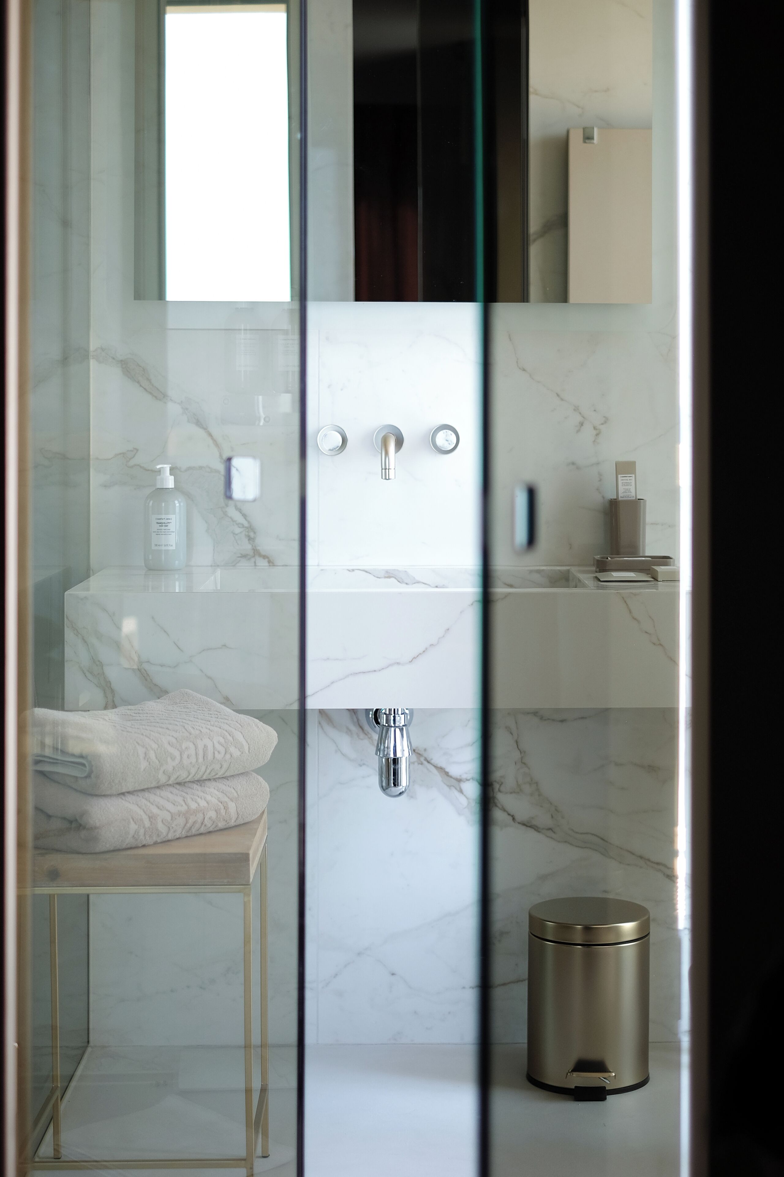 A modern bathroom with a glass-enclosed shower, a marble sink, and a toilet.