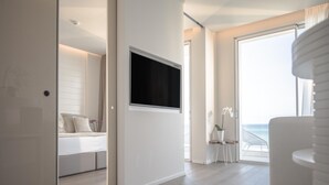 A modern bedroom with a bed, a TV mounted on the wall, and a balcony with a view of the sea. - Hotel Sans Souci (Gabicce Mare)