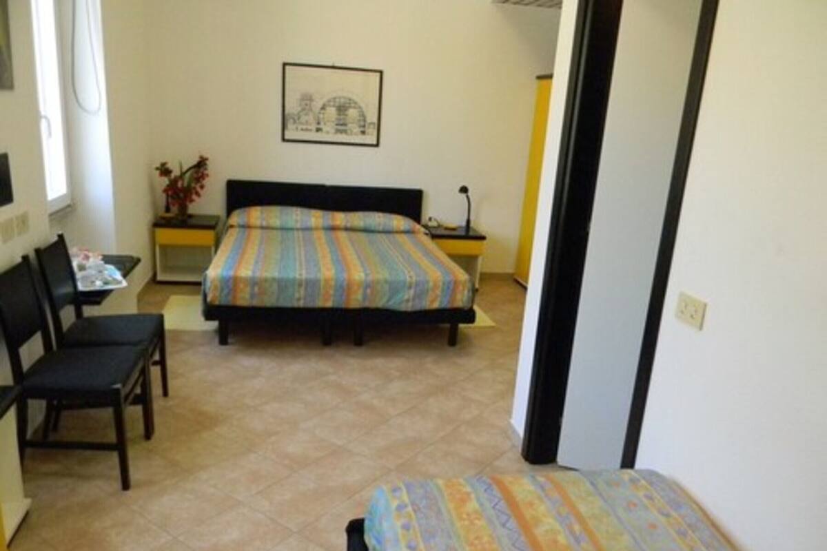 A bedroom with a bed, a chair, a desk, and a small table.