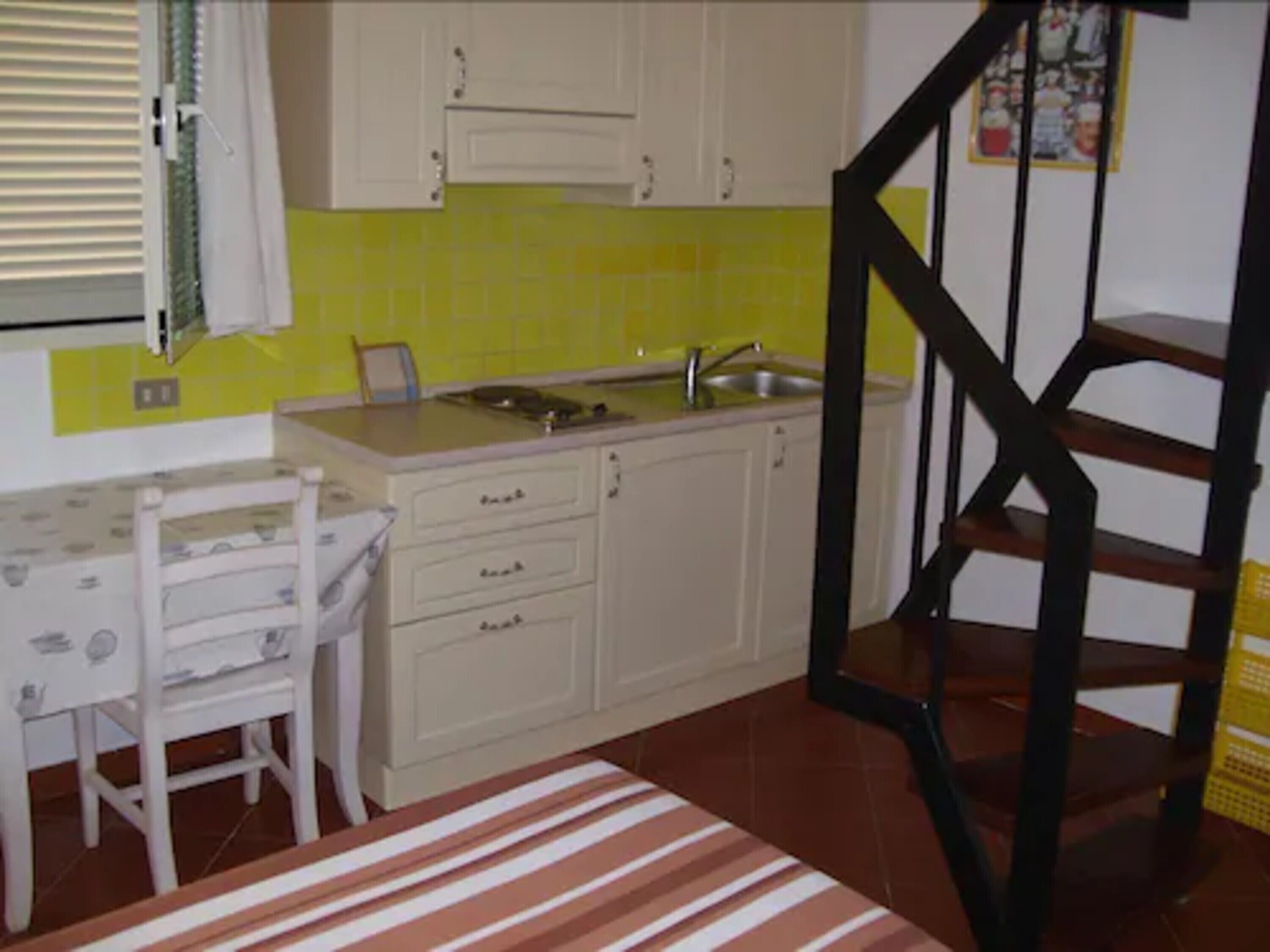 A kitchen with a sink, cabinets, and a dining table with chairs.