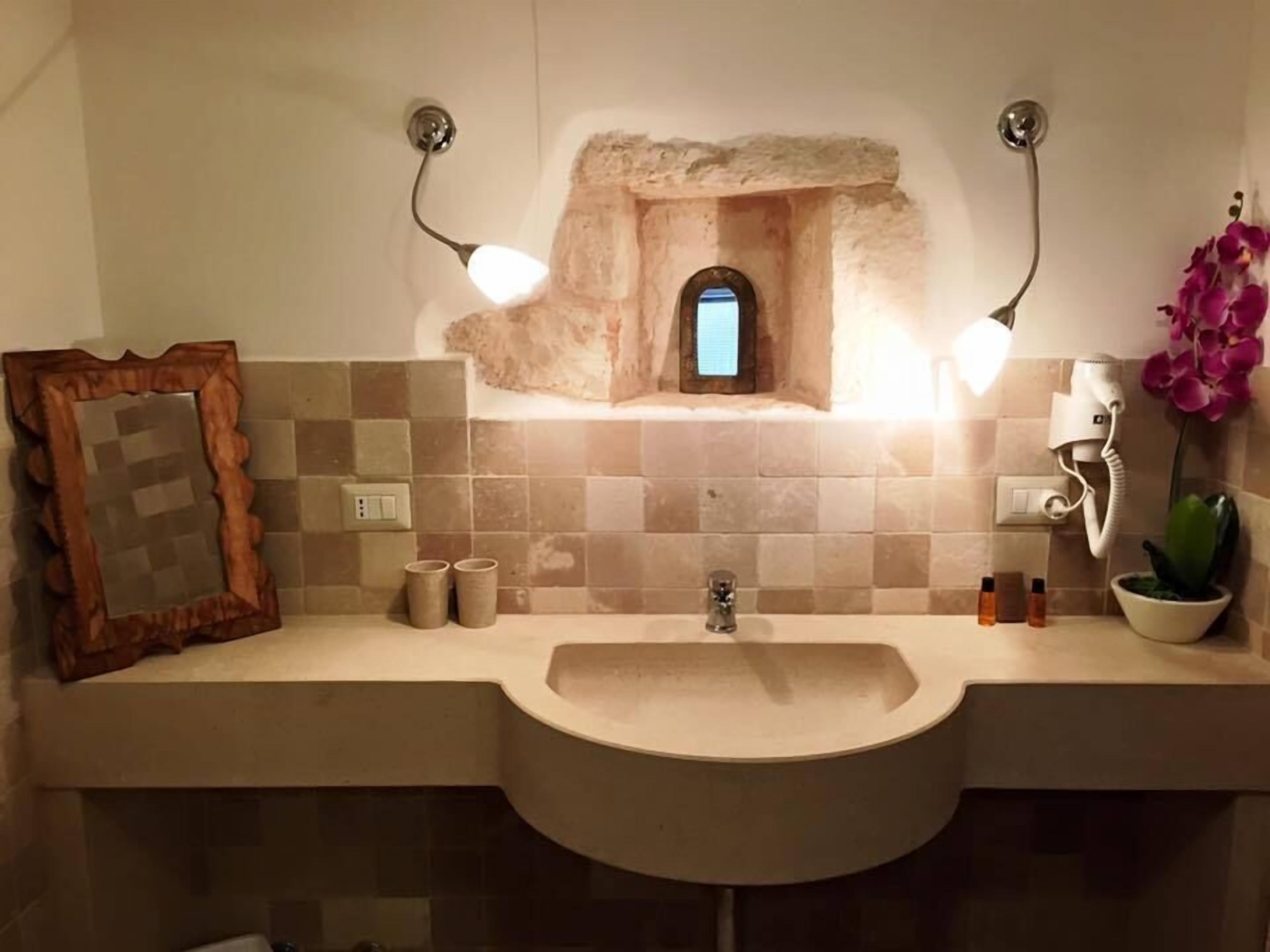 Ein Badezimmer mit Waschbecken, Spiegel und einem kleinen Fenster.
