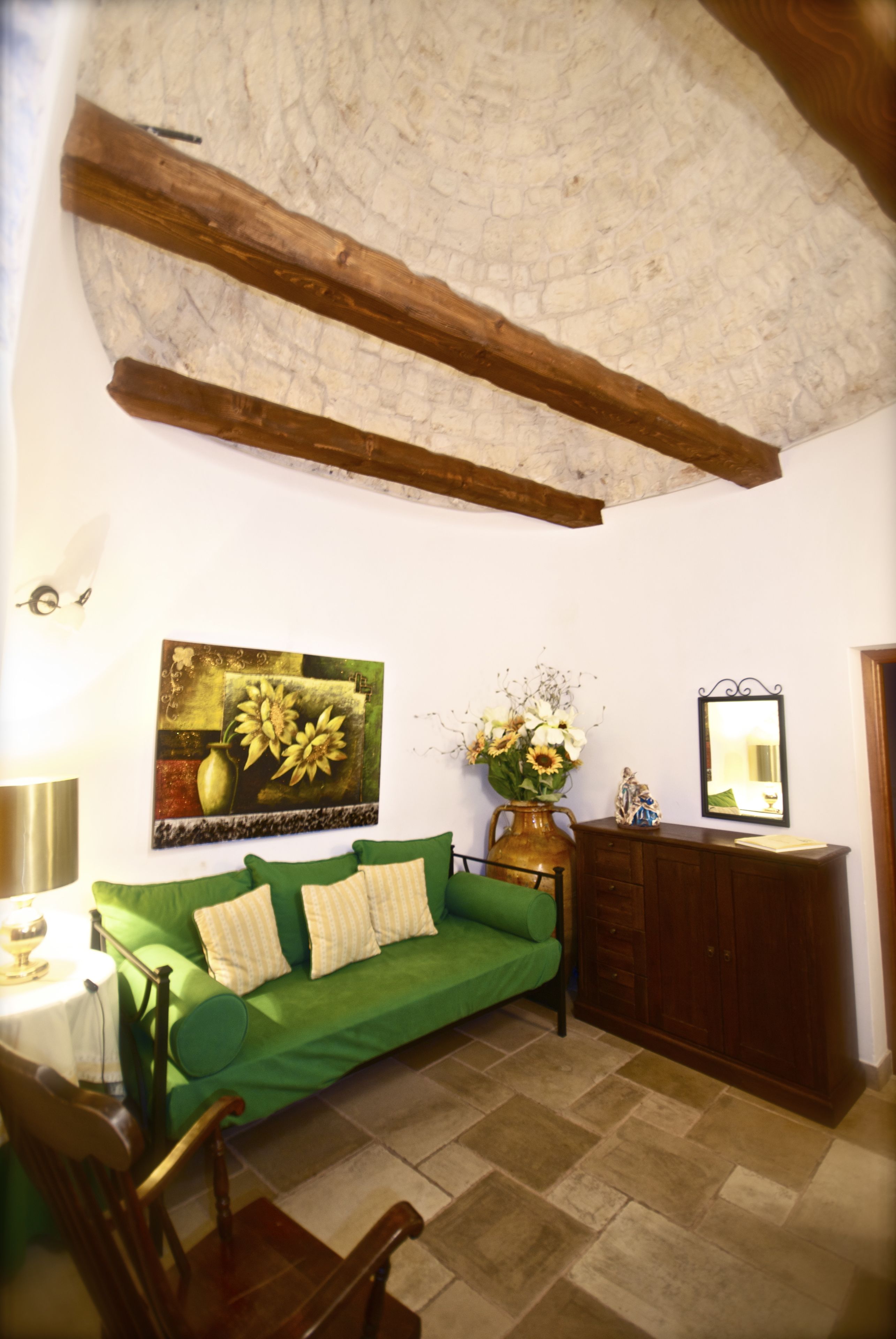 A cozy room with a green sofa, a wooden cabinet, and a painting on the wall.