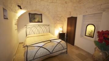 A bedroom with a bed, a nightstand, a lamp, a picture on the wall, and a window with a view.