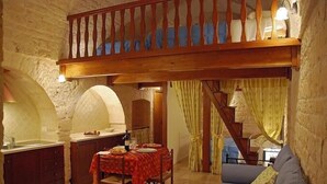 A cozy dining area with a wooden table set for two, a kitchen with a sink and counter, and a staircase leading to an upper level. - Trulli e Puglia (Alberobello)