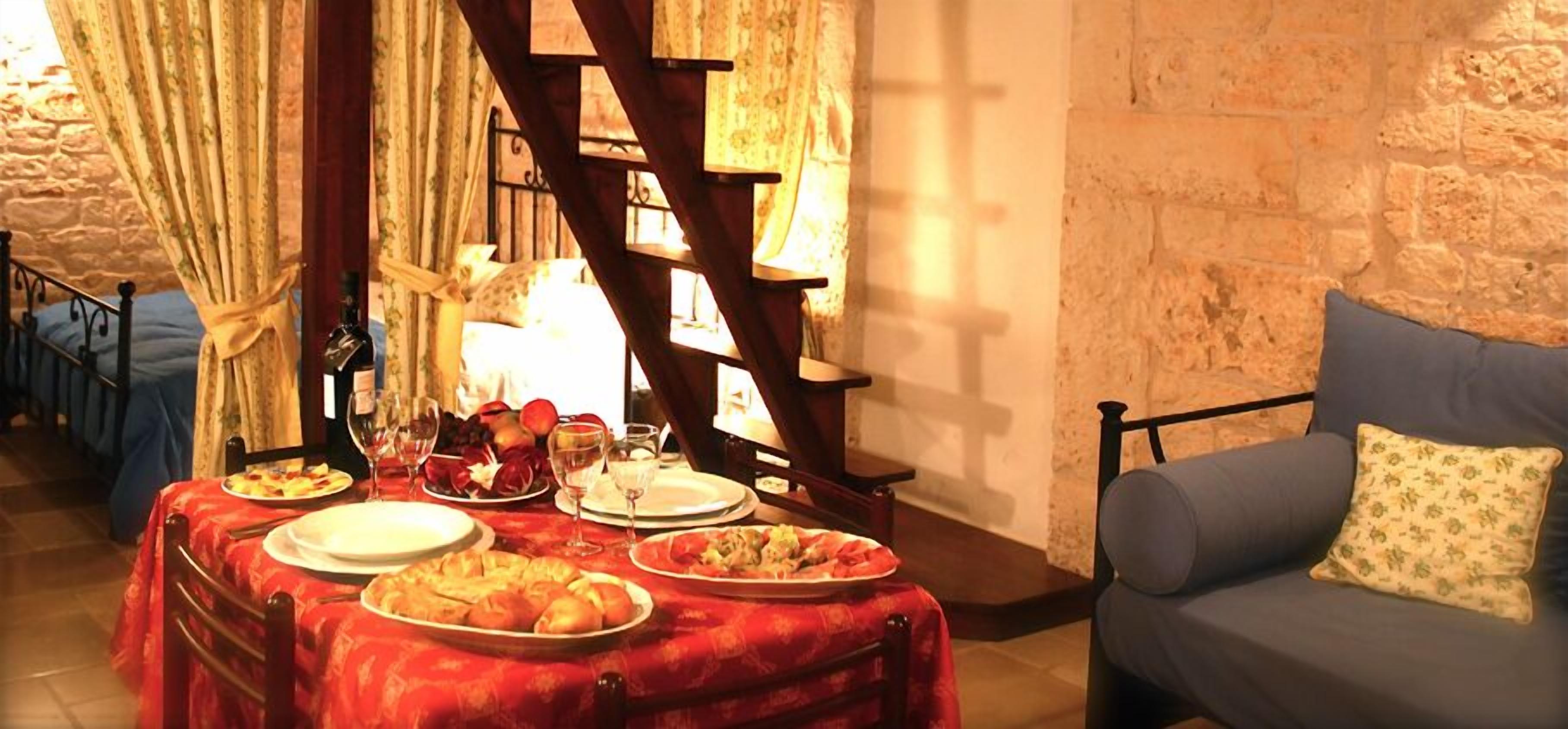 A dining area with a table set for a meal, a staircase, and a couch.