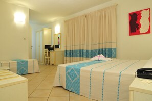 Ein Hotelzimmer mit zwei Betten, einem Schreibtisch, einem Stuhl und einem Badezimmer im Hintergrund.
