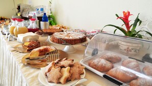 Noutopöytä, jossa on tarjolla erilaisia leivonnaisia, kuten kakkuja, piirakoita ja leipää.