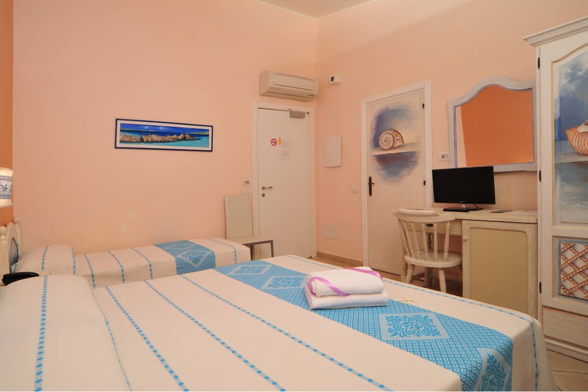 Habitación de hotel con dos camas, un escritorio, una silla, un televisor y una puerta con un cartel de no fumar.