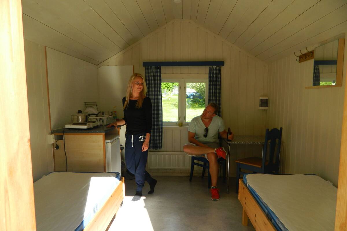 Allotjament petit d'una sola habitació amb dues places, una cuineta i una finestra amb cortines.