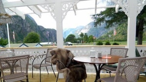 A covered outdoor seating area with a wooden table and metal chairs, overlooking a mountainous landscape. - Eidfjord Gjestgiveri (Eidfjord)