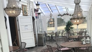 A covered patio area with wooden flooring, wicker furniture, and hanging lanterns. - Eidfjord Gjestgiveri (Eidfjord)