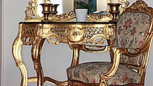 A room with a gold-framed mirror, a floral-patterned chair, and a small table with a vase and candle. - Eidfjord Gjestgiveri (Eidfjord)
