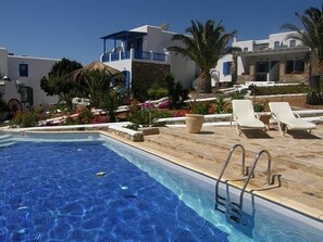 A swimming pool with lounge chairs and a stone deck. - Blue Dolphin Antiparos Villas and Suites (Antiparos)