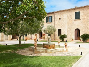 A courtyard with a fountain, stone building, and potted plants. - Agroturismo Puig de Ros d'Alt (Llucmajor)
