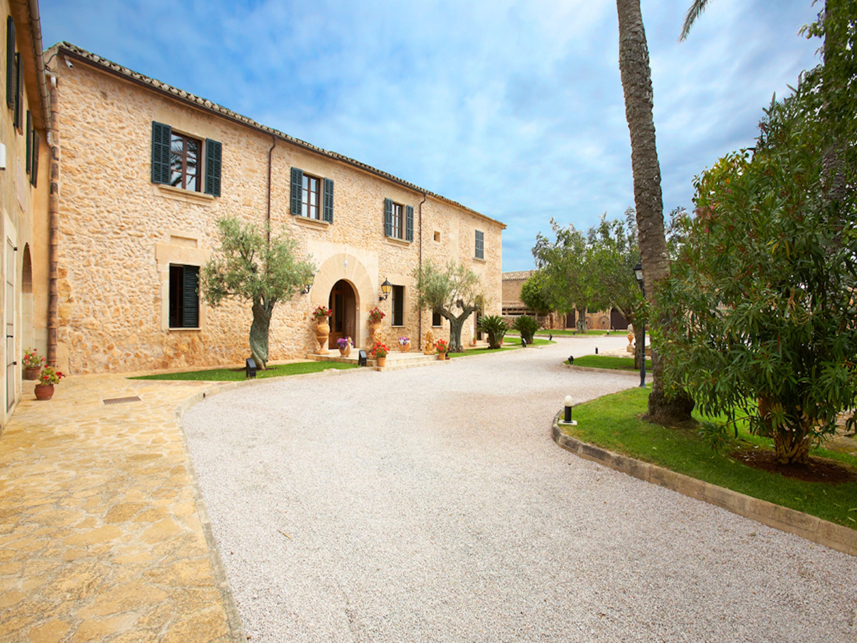 A stone building with a courtyard, featuring a central archway and potted plants.