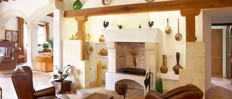 A spacious living room with leather armchairs, a fireplace, and rustic decor.