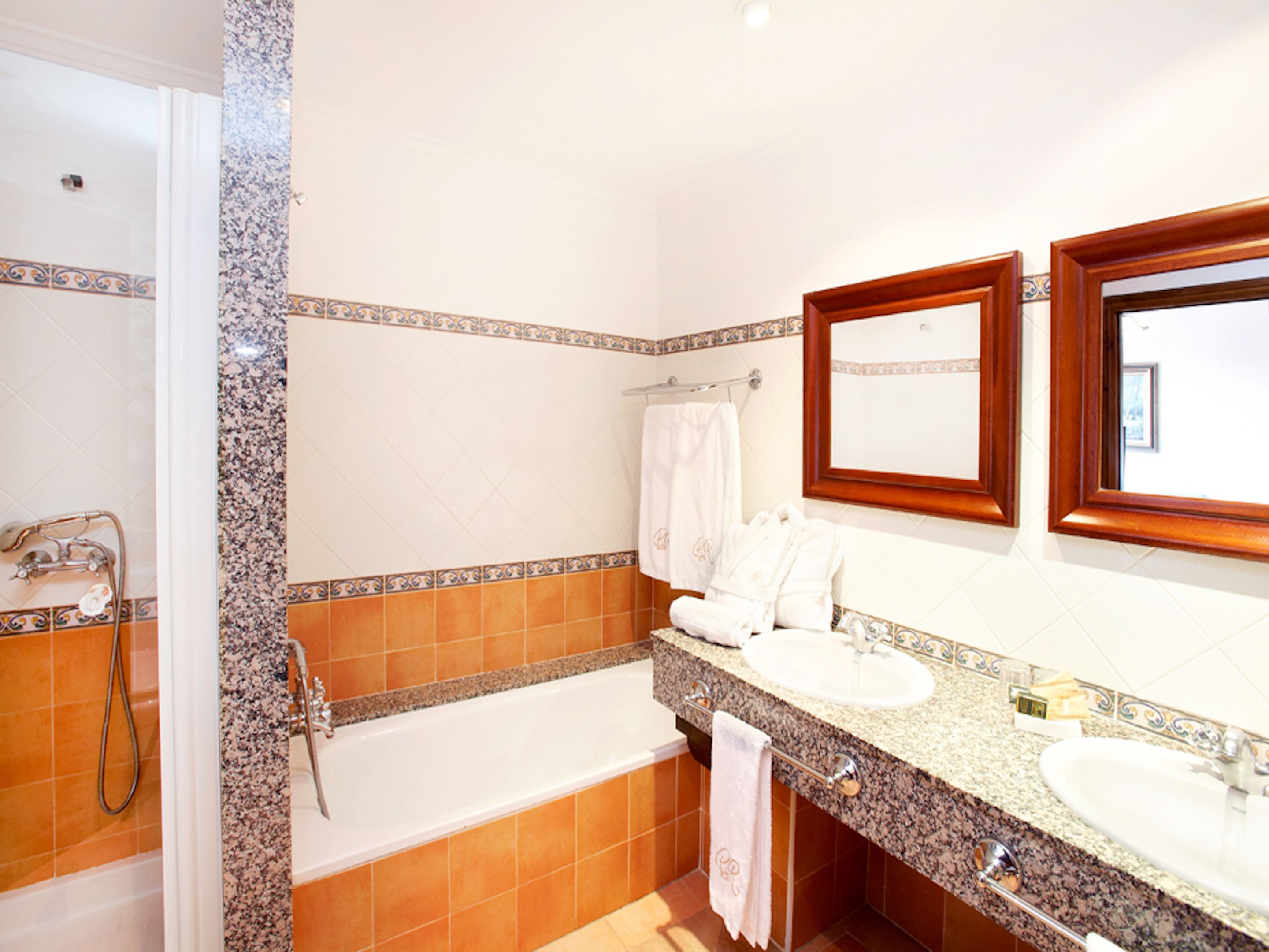 Un baño con dos lavamanos, una bañera y una ducha.