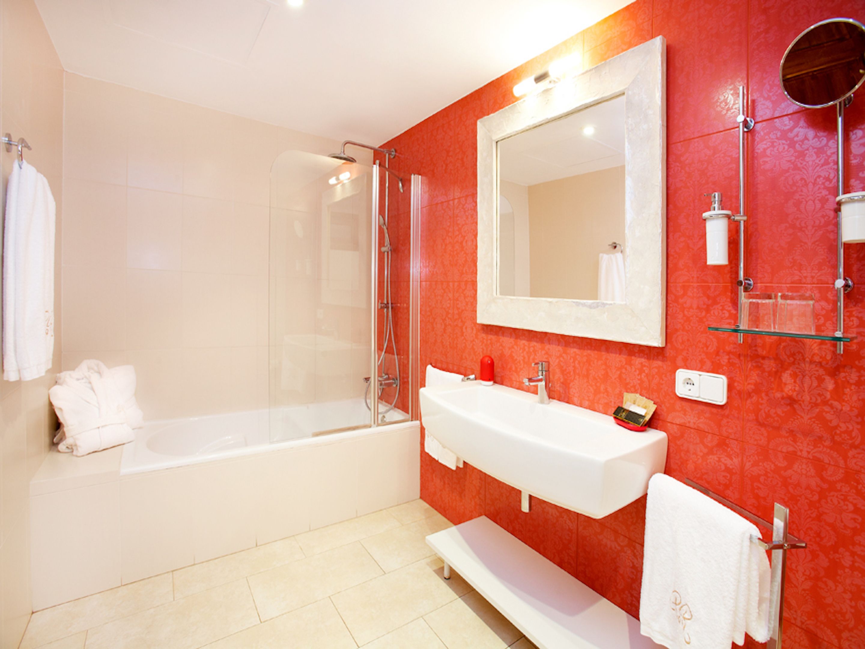 Une salle de bain moderne avec une douche à parois de verre, une baignoire blanche et un grand miroir au-dessus d’un lavabo blanc.