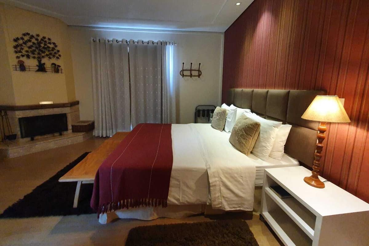 Une chambre d’hôtel avec un lit, une table de chevet, une lampe et une cheminée.