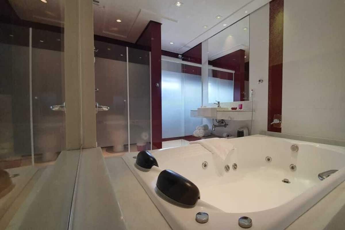 Une salle de bain moderne dotée d’une grande baignoire, d’une douche à parois de verre et d’un meuble-lavabo avec un miroir.