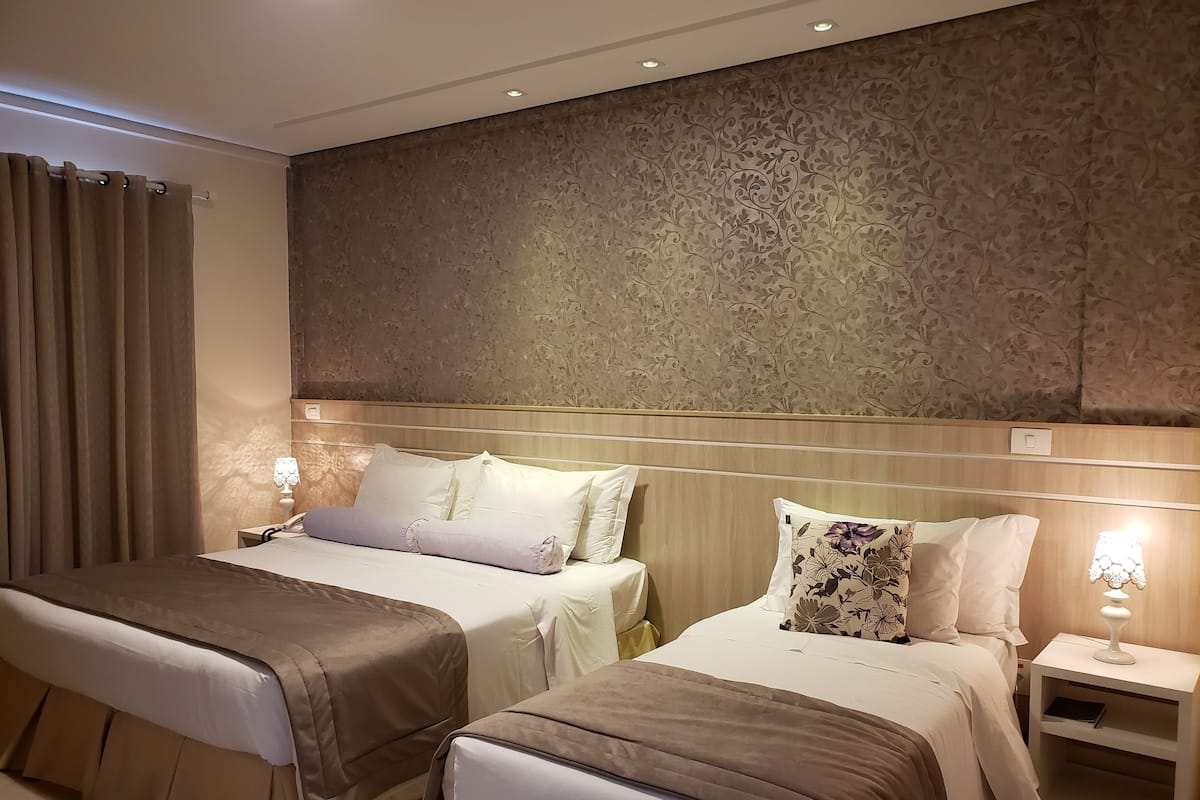 Une chambre d’hôtel avec deux lits, une table de chevet avec une lampe et un mur décoré d’un motif.