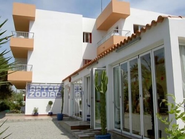 Ein modernes Gebäude mit weißer Fassade, mehreren Balkonen und großen Glaseschauern.