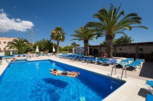 Una piscina al aire libre, sillones reclinables de piscina