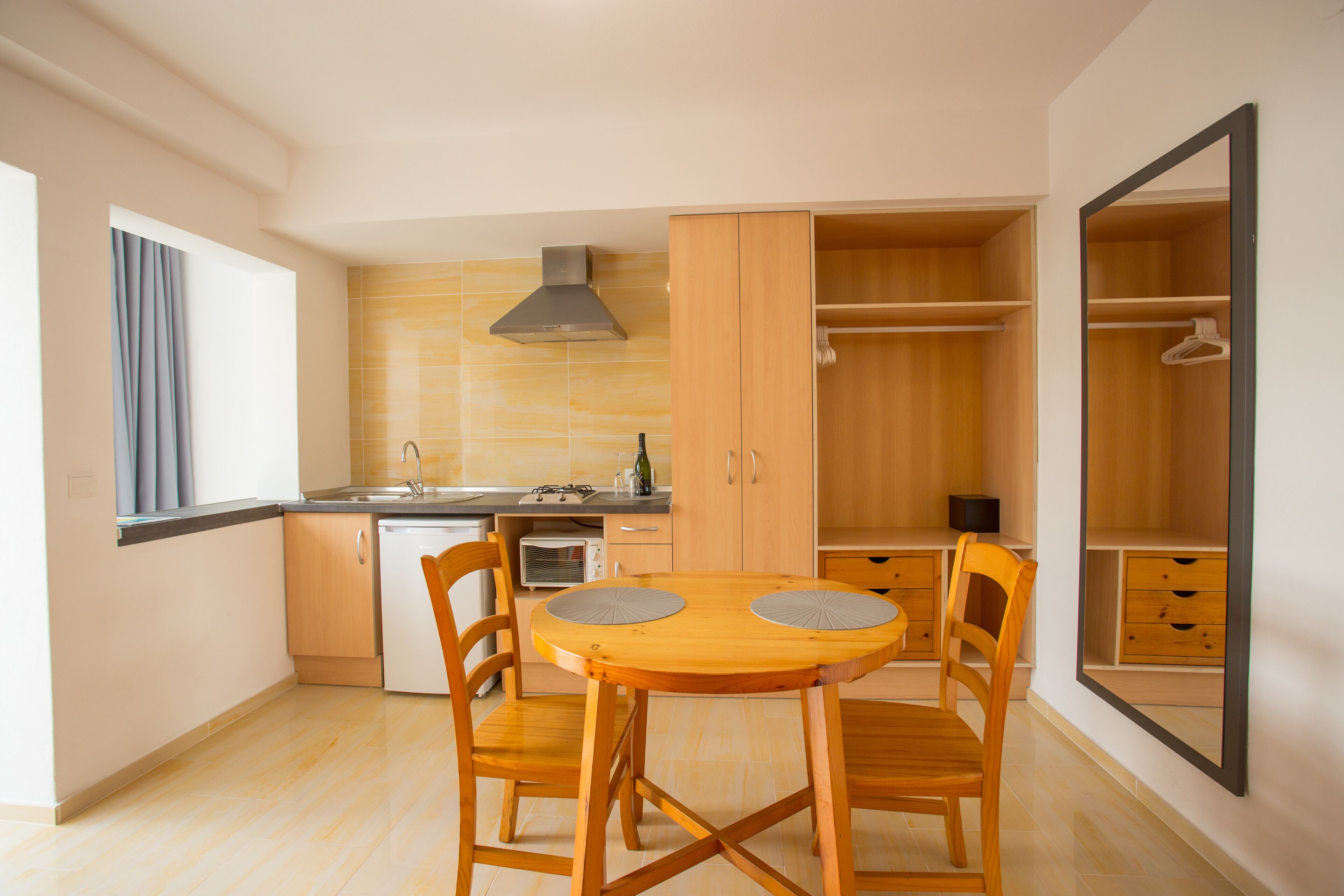 A compact kitchen with a dining table, chairs, and a built-in oven.