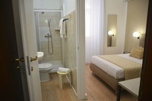 Una habitación de hotel con ducha, inodoro y cama.