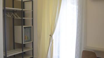 Una camera da letto con un letto, un armadio, una sedia e un televisore appeso al muro.