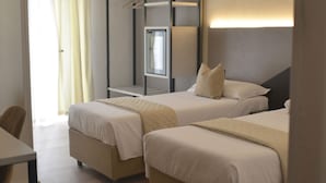 Habitación de hotel con dos camas, un escritorio y una ventana con cortinas.