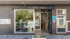 The exterior of Mar Calma Hotel with a large glass window displaying a 'love store' sign, a reception area, and a wheelchair accessibility sign. - Mar Calma Hotel (Pollenca)