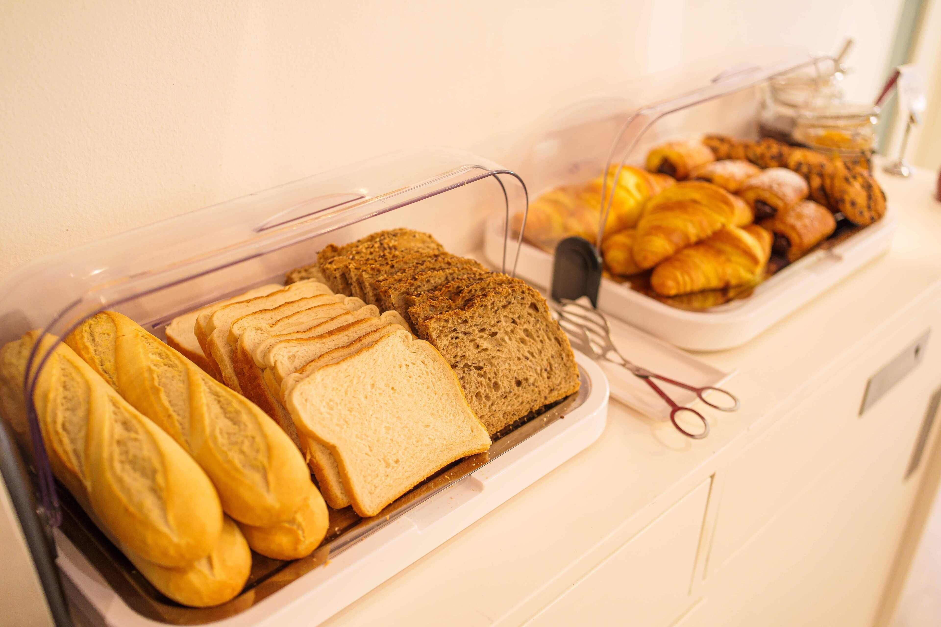 En frukostbuffé med ett urval av olika brödsorter och bakverk.