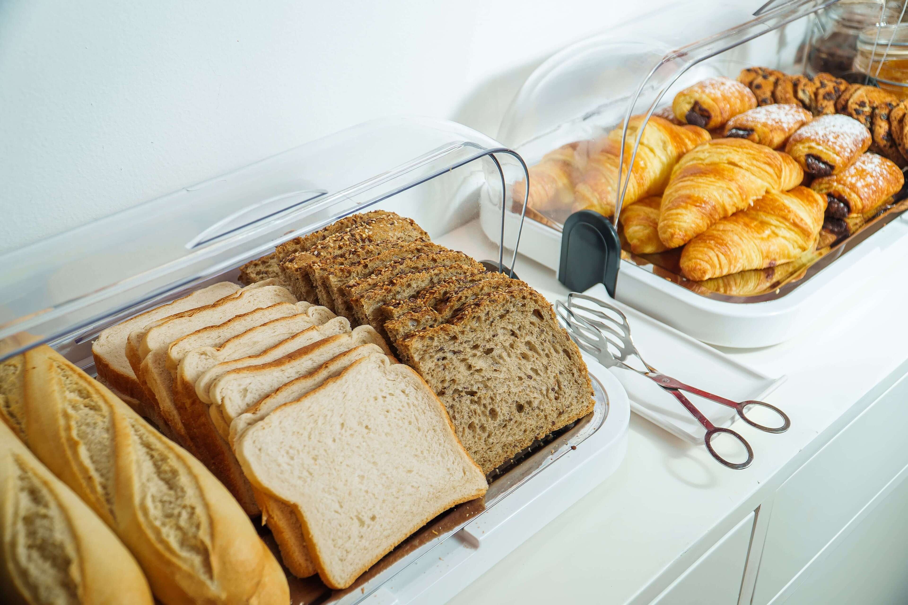 Un ricco buffet per la colazione con pane a fette, croissant e dolci.