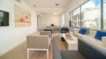 A modern living room with a sofa set, a coffee table, and a TV mounted on the wall.