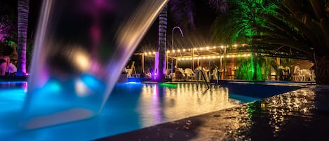 Una piscina al aire libre, sombrillas, sillones reclinables de piscina