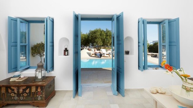Una stanza con vista su una piscina, un settimino in legno e un vaso con fiori.