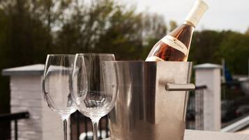 Une bouteille de vin dans un seau en métal, avec deux verres à vin vides à côté.