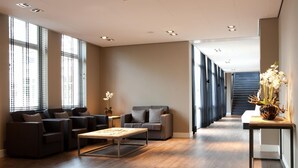 Een moderne woonkamer met een zithoek, een bijzettafeltje en een potplant.