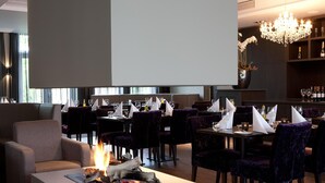 Een restaurant met een open haard, eettafels, stoelen en een bar.