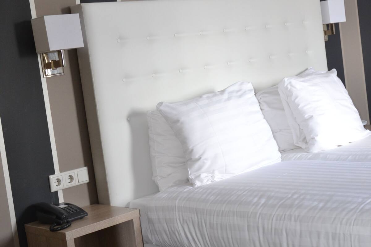 Une chambre d’hôtel avec un grand lit, une table de chevet avec un téléphone et un mur à rayures verticales.