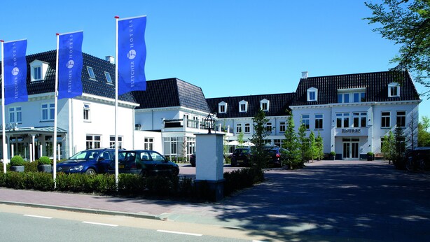 Een hotel in traditionele Europese stijl, met een opvallende ingang, meerdere ramen en een goed onderhouden oprit.