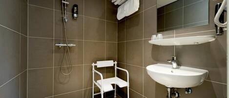 A modern bathroom with a shower, a white chair, and a sink.