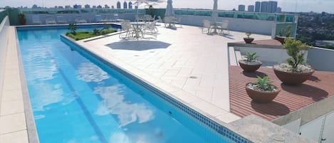 Una piscina al aire libre, sombrillas, sillones reclinables de piscina