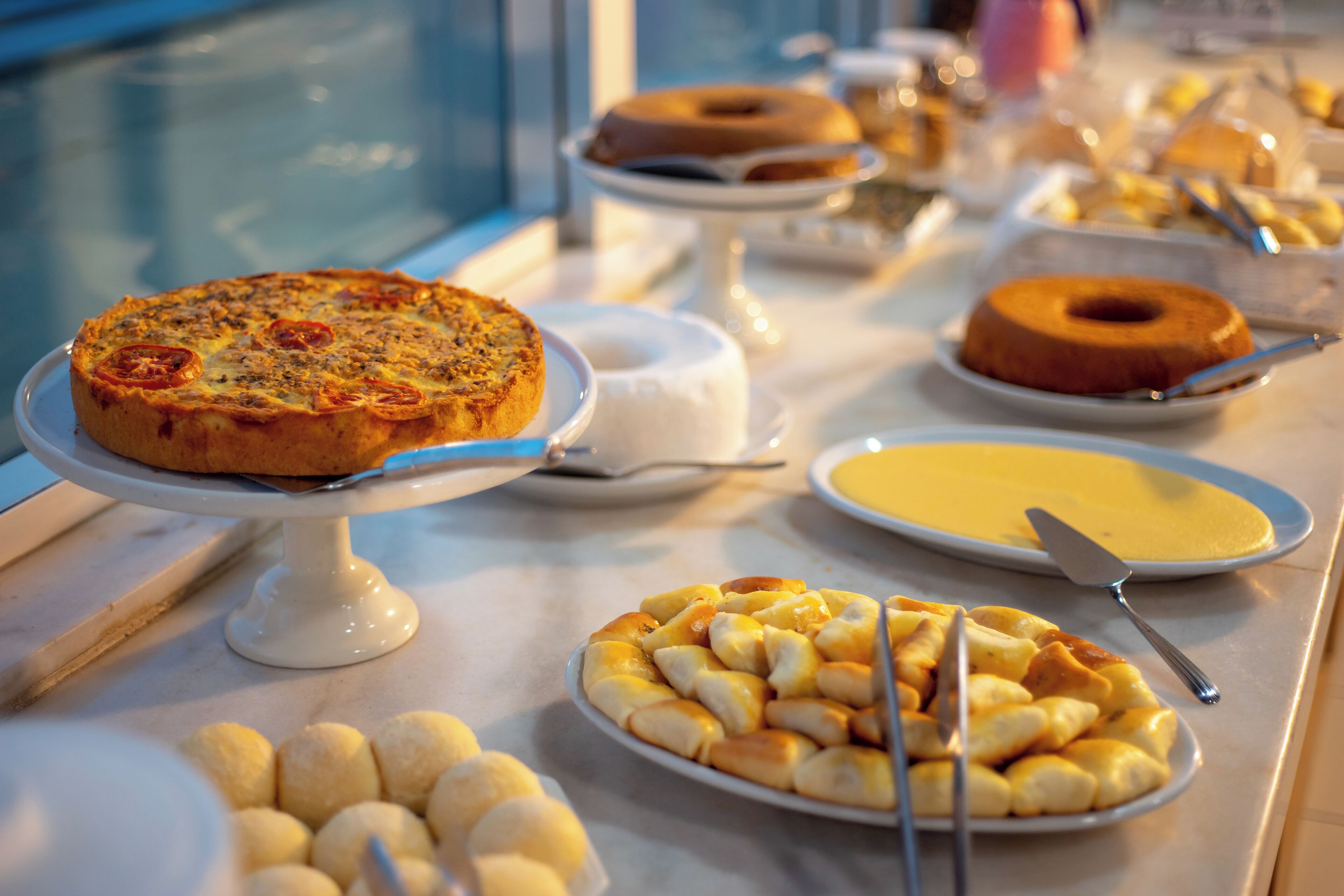 Un bufet ple de plats variats, incloent pizza, pastís bundt i altres postres.