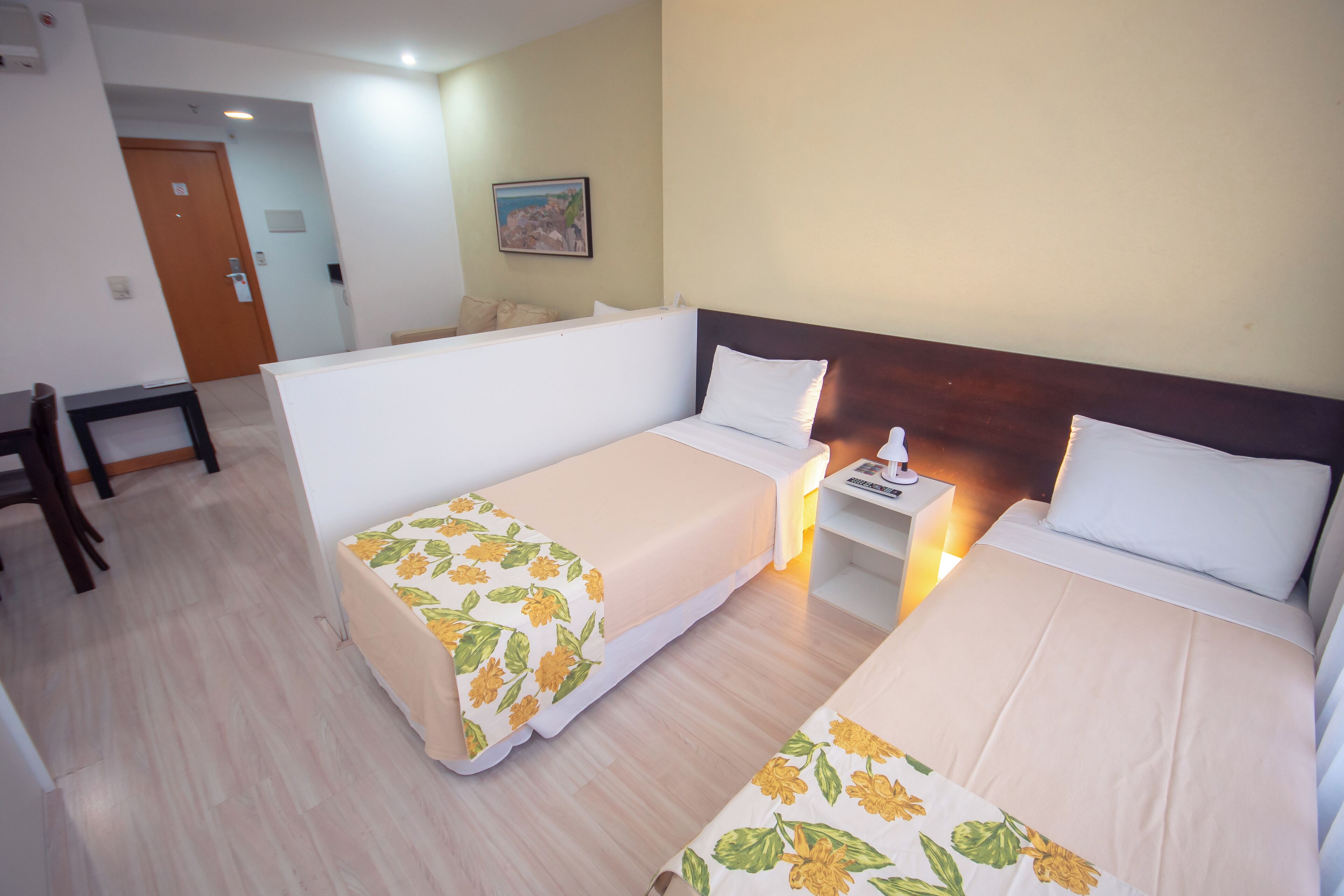 Habitació d'hotel amb dos llits, una taula de treball i una cambrera de nit.