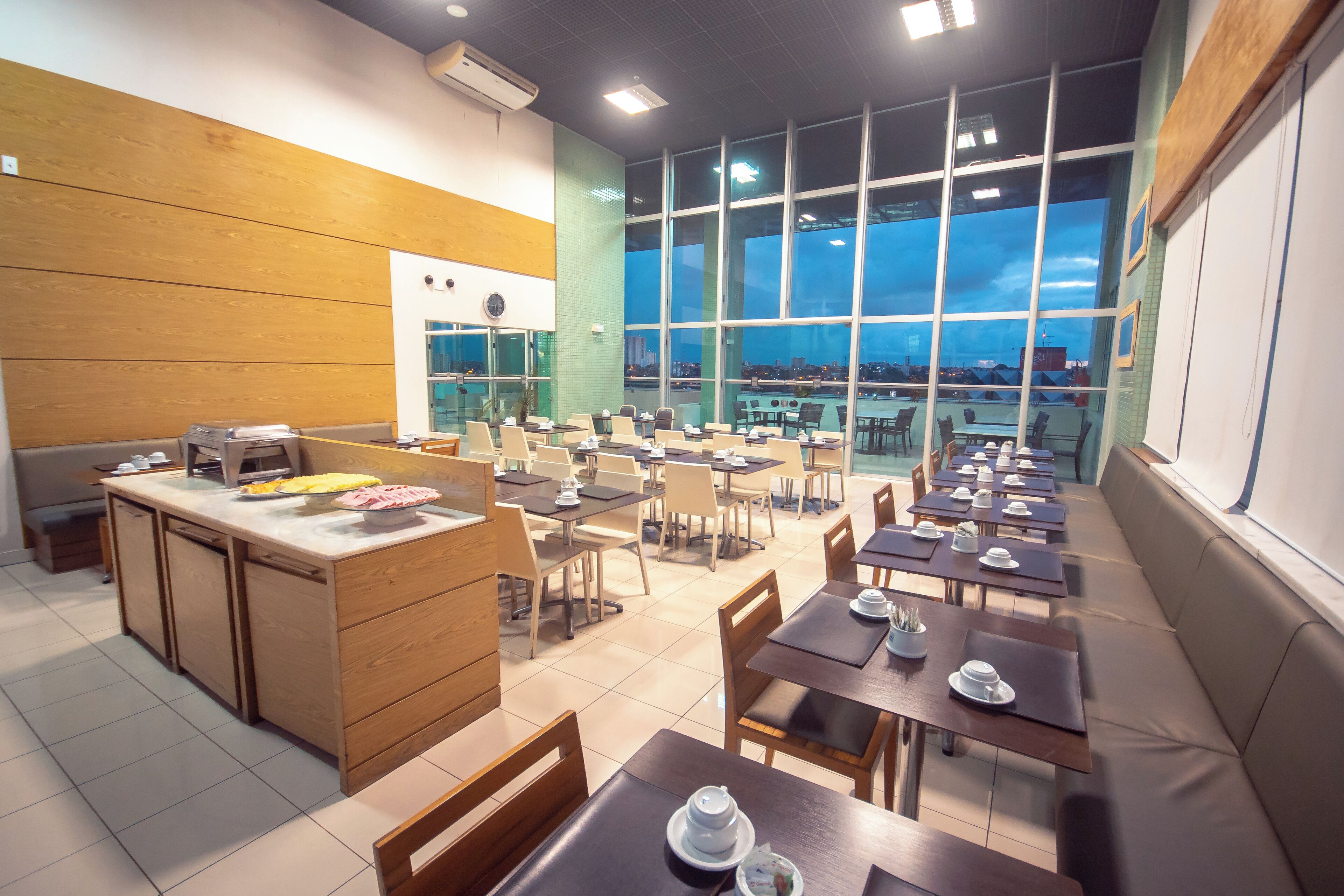 A modern dining area with a kitchen counter, multiple tables, and chairs.