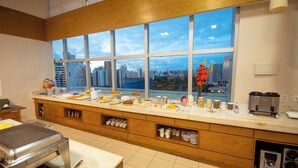 A modern kitchen with a large window, a buffet setup, and a coffee machine.