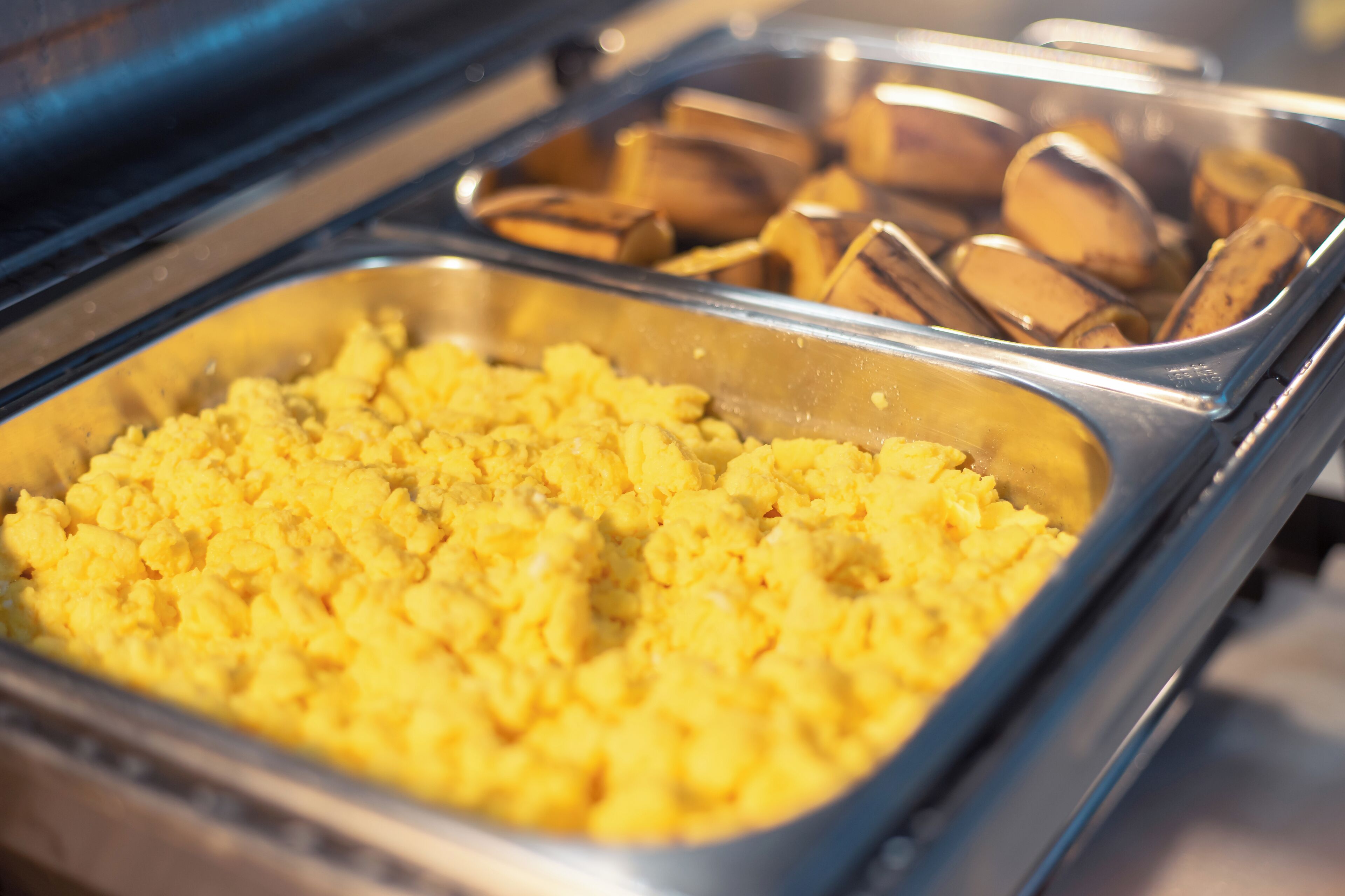 A buffet with scrambled eggs and sliced bananas.